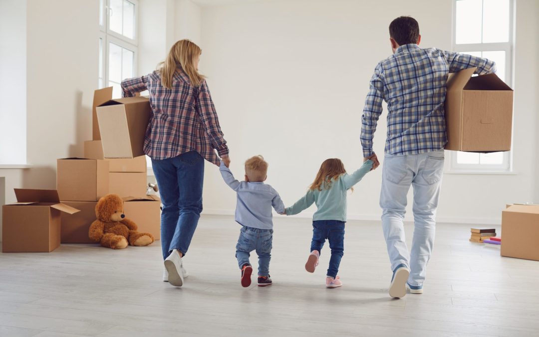 Happy Family With Children Moving With Boxes In A New Apartment House.